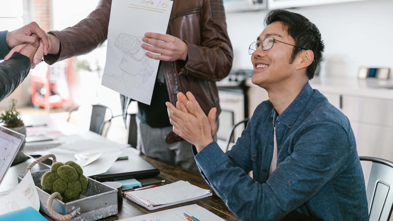 Équipe de petite entreprise célébrant la signature d’un accord commercial autour d’une table